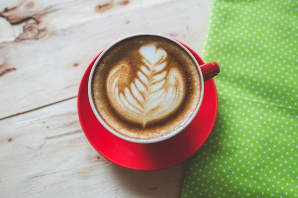Ahşap arka plan üzerinde kırmızı kahve latte sanat Kupası. — Stok fotoğraf