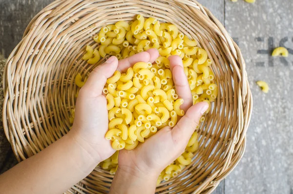 Italské těstoviny makarony v dětské ruce. — Stock fotografie