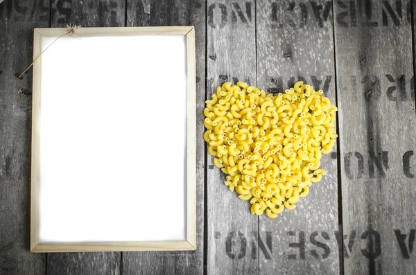 Coeur en forme de macaroni symbole et tableau blanc sur fond en bois — Photo