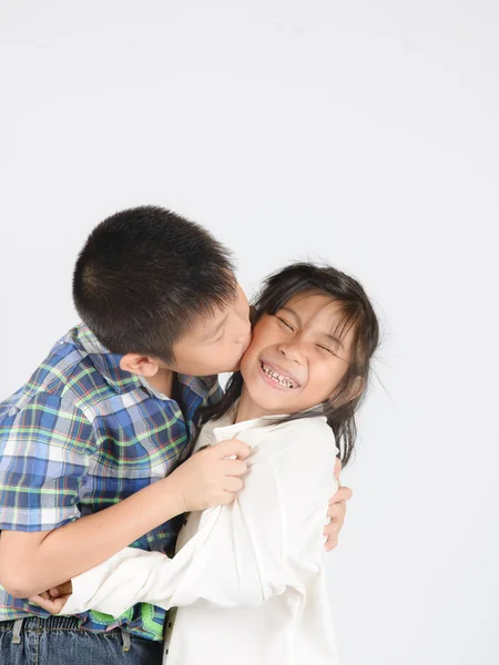 Hermano cariñoso y hermana pequeña abrazándose sobre fondo gris . — Foto de Stock