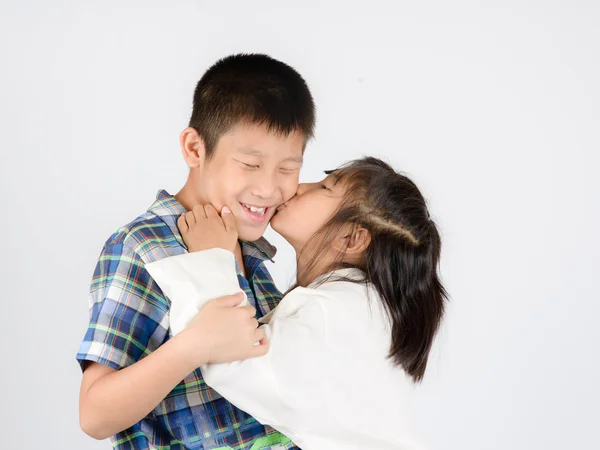 Люблячий брат і маленька сестра обіймаються на сірому фоні . — стокове фото
