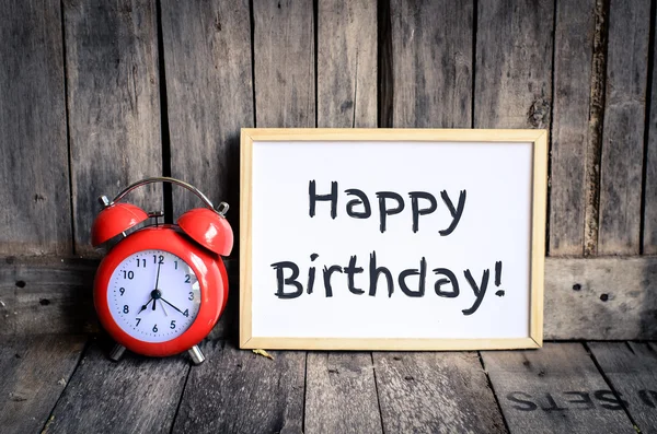 Happy birthday messae on white board and red retro clock by wooden background — Stock Photo, Image