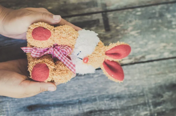 Bambola coniglio in mani di bambino, concetto pasquale con tono vintage . — Foto Stock