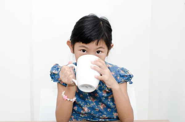 Asiática chica sosteniendo una taza de leche durante el desayuno en casa . — Foto de Stock