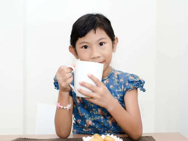 Asiática chica sosteniendo una taza de leche durante el desayuno en casa . — Foto de Stock