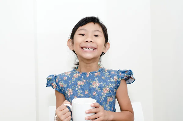 Asiática chica sosteniendo una taza de leche durante el desayuno en casa . — Foto de Stock