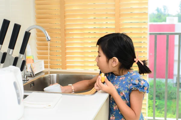 Asian girl washing white cup in kitchen. — Stock Photo, Image