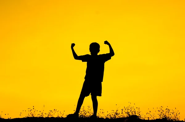 Chlapec, zvedá ruce stojící při západu slunce — Stock fotografie