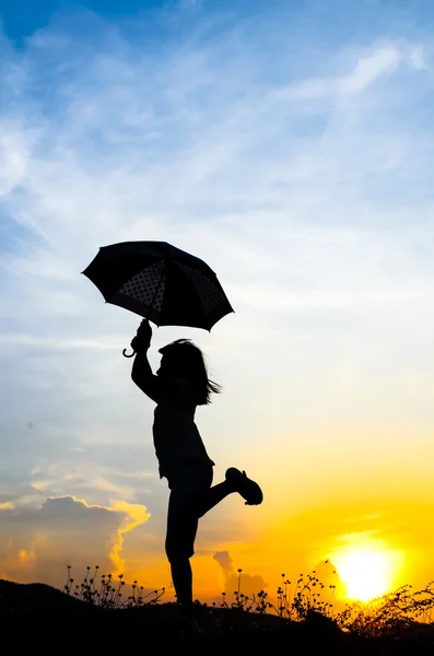 Motion blur jumping Umbrella girl with sunset silhouette — Stock Photo, Image