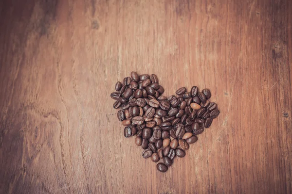 Herzform aus Kaffeebohnen auf Holzoberfläche. — Stockfoto