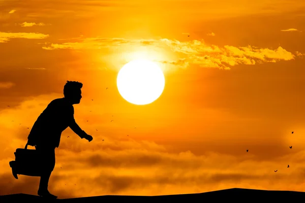 Silhueta de um homem de negócios com labtop correndo com nascer do sol . — Fotografia de Stock