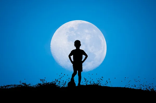 Boy with soccer ball, big moon and grass silhouettes background — Stock Photo, Image