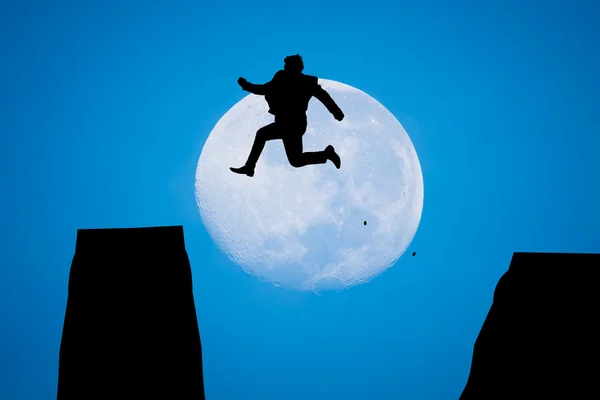 Silhueta homem pulando no sol subir com grande lua — Fotografia de Stock