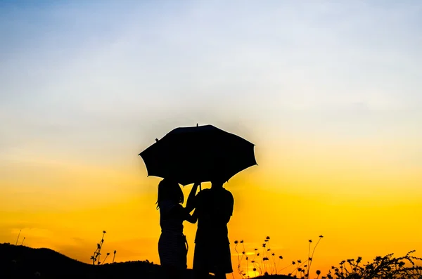 Guarda-chuva menina e menino com silhueta pôr do sol — Fotografia de Stock