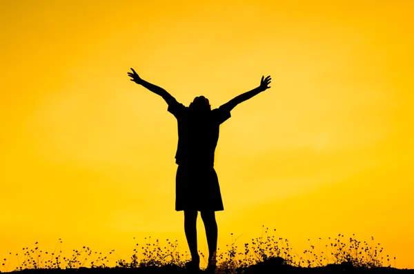 Jongen verhogen zijn handen permanent tijdens zonsondergang — Stockfoto