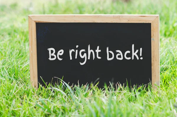 Worden recht terug bericht op blackboard op groen gras. — Stockfoto