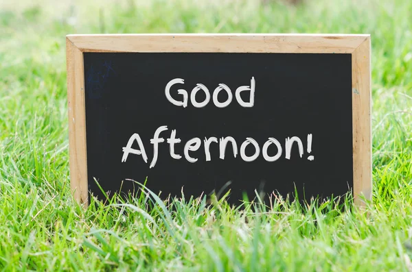 Good afternoon message on blackboard on green grass. — Stock Photo, Image