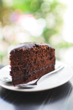 Dilim karanlık çikolatalı kek bokeh arka plan ile.