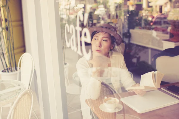 Asiatisk kvinna läser bok i café. — Stockfoto