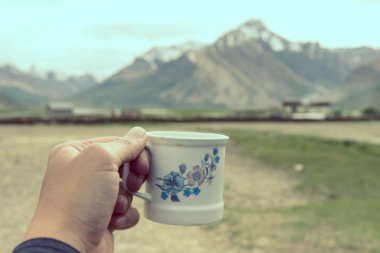 Hand holding coffee cup with Himalaya Mountain background, Rangd clipart