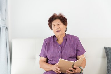 Yaşlı kadın evde kitap okuyor..