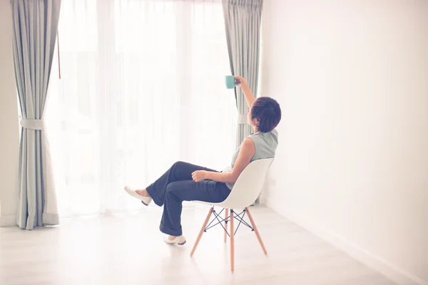 Vrouw thuis zittend op moderne stoel — Stockfoto