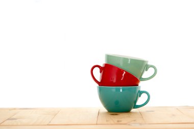 Ahşap masa ve beyaz arka plan üzerinde renkli kahve bardağı.