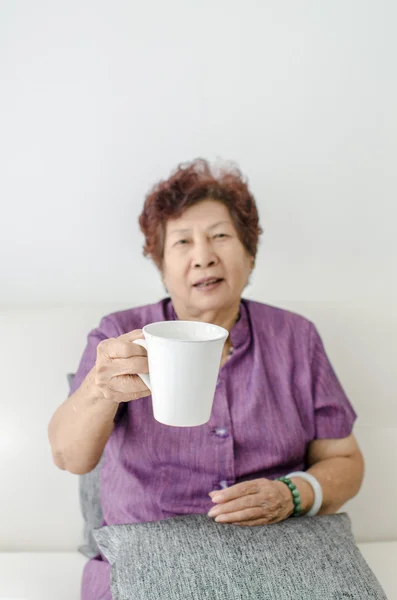 Stará žena s šálkem kávy nebo čaje doma. Selektivní zaměření. — Stock fotografie