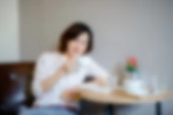 Размытый фон: женщина сидит в кафе и пьет с — стоковое фото