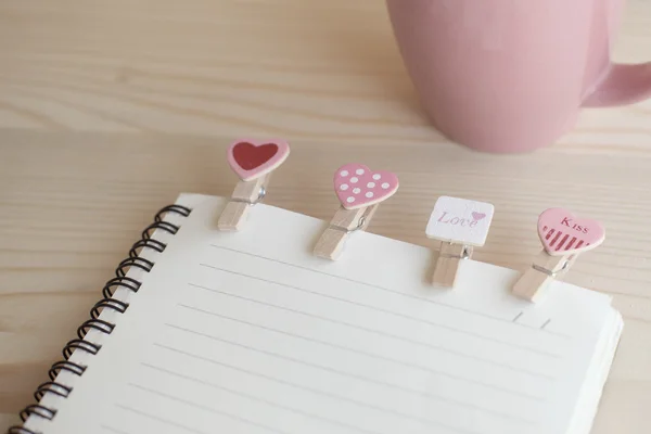 Clipes de madeira em forma de coração com notebook em madeira de pinho . — Fotografia de Stock
