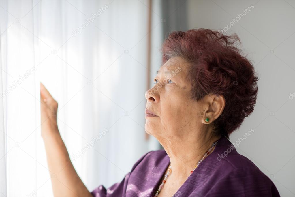 Portrait of Asian elderly woman holding white curtain with natur