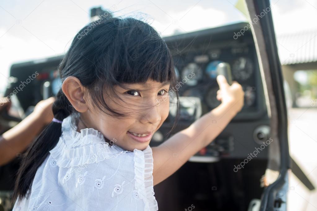 Asian girl in cockpit of plane with sunny day.