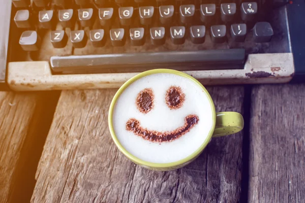 Taza de café feliz y máquina de escribir Vintage sobre fondo de madera . — Foto de Stock