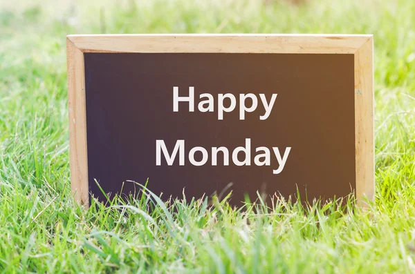 Happy maandag opmerking op blackboard op groen gras. — Stockfoto