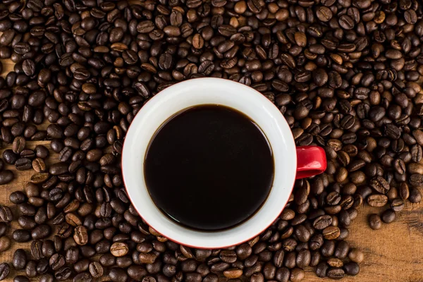 Taza de café y granos de café en la mesa de madera —  Fotos de Stock