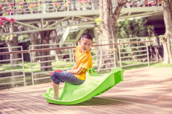 Glücklich asiatische Junge auf dem Spielplatz am Tag Zeit, vintage Ton. — Stockfoto