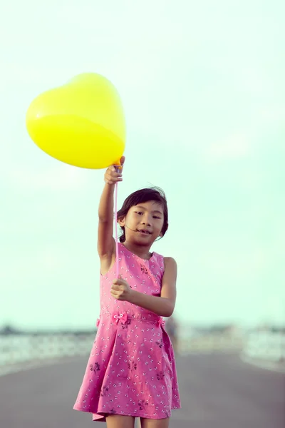 Asian girl holding yellow balloon with vintage tone. — Stock Photo, Image