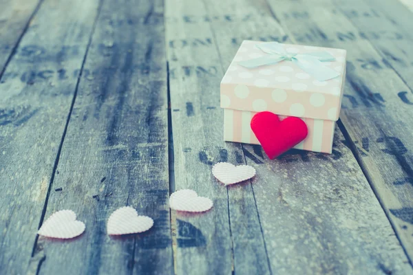 Gift box and red heart shape on wooden table. — Stock Photo, Image