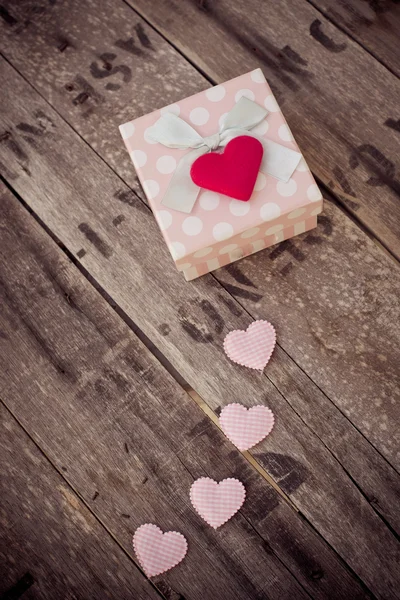 Ahşap masa üzerinde hediye kutusu ve kırmızı kalp şekli. — Stok fotoğraf