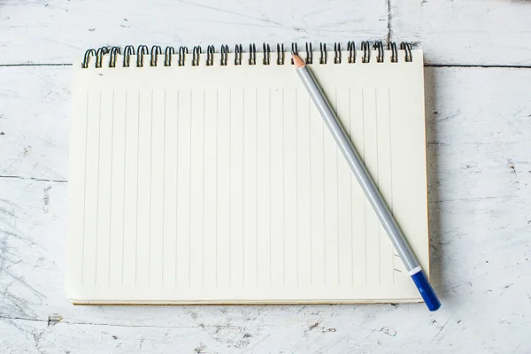 Cuaderno de papel y lápiz sobre fondo de madera blanco . — Foto de Stock