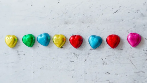 Corações de chocolate coloridos em fundo de madeira . — Fotografia de Stock