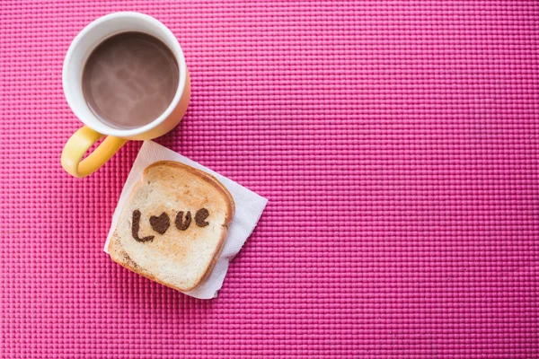 Liebesbotschaft auf Brot in Scheiben geschnitten und Schokotasse auf rosa Yoga — Stockfoto