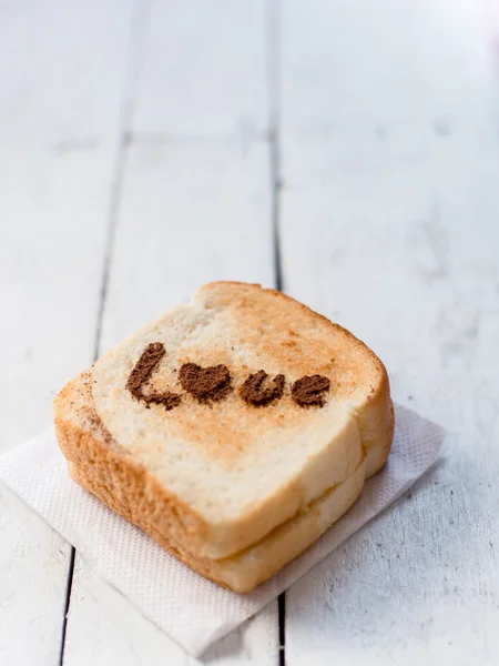 Love message on Bread sliced on white wooden background. — Stock Photo, Image