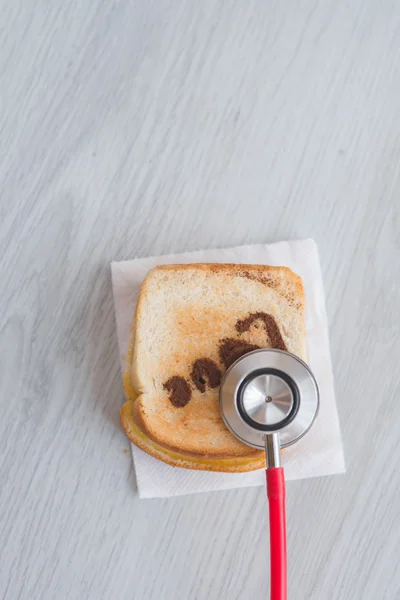 Red medische stethoscoop en gesneden brood op grijze achtergrond. — Stockfoto