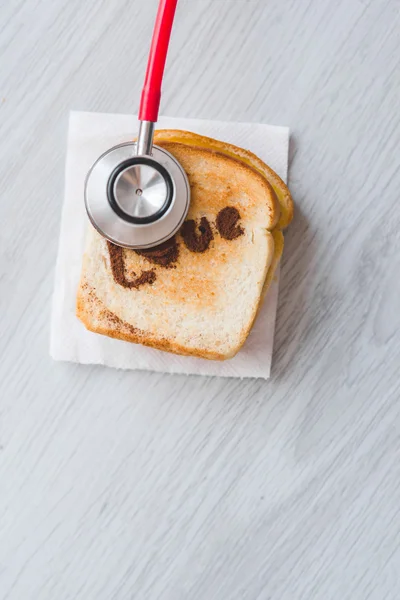 Röd medicinska stetoskop och skivat bröd på grå bakgrund. — Stockfoto