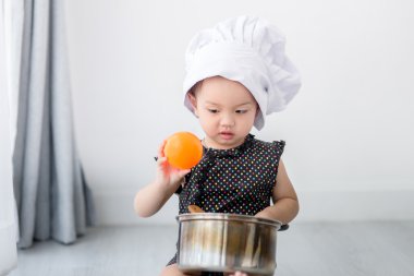 Asyalı çocuk evde aşçıyı oynuyor..