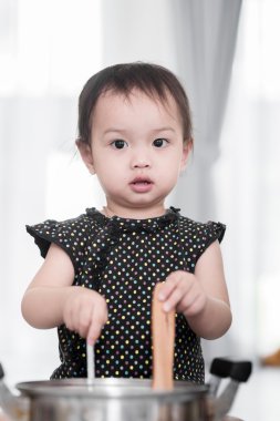 Asyalı çocuk evde aşçıyı oynuyor..