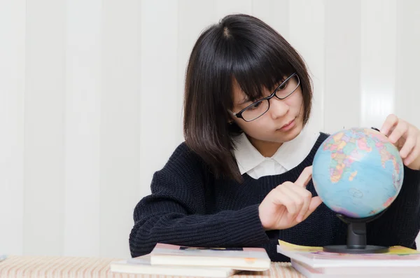 Adolescente écolière pointant une place sur un globe avec son doigt — Photo
