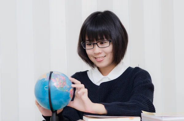 Школярка-підліток вказує місце на глобус своїм пальцем — стокове фото