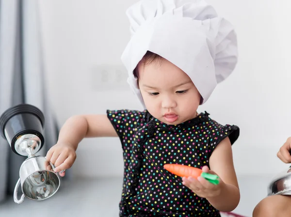 Aziatisch kind spelen een chef-kok thuis. — Stockfoto